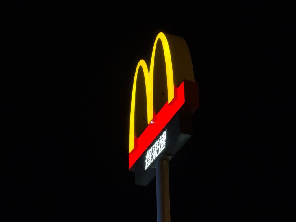 Bright McDonalds sign against a dark sky, showcasing iconic golden arches.