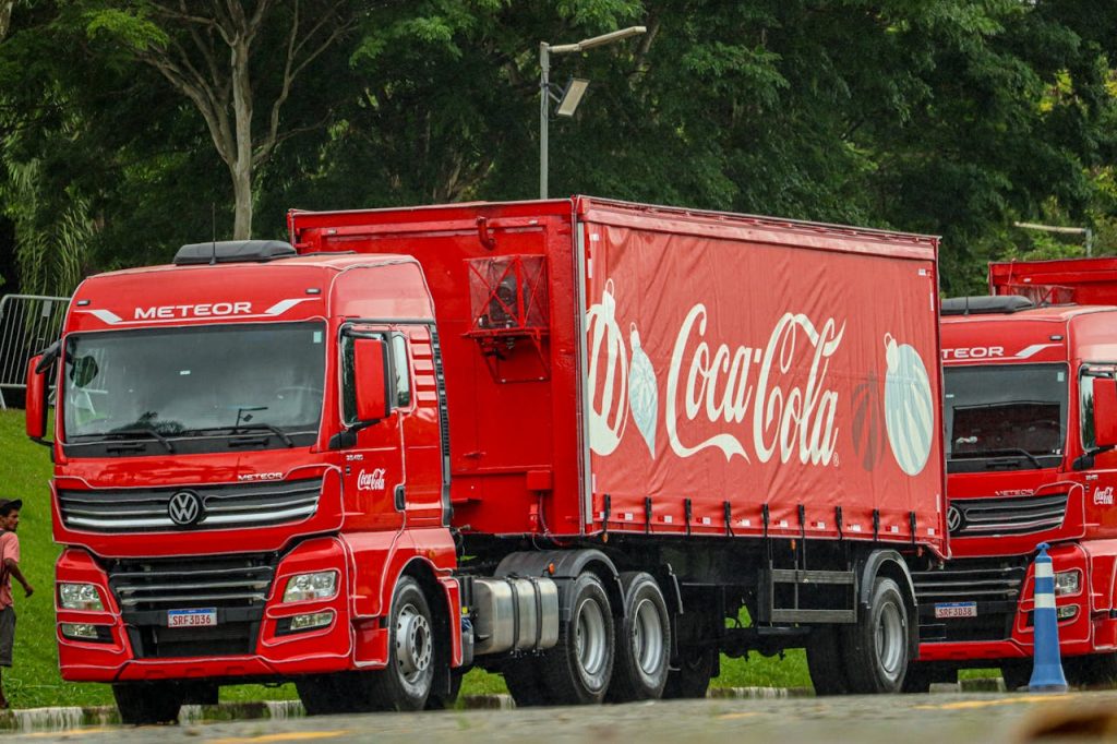 Red Coca-Cola truck parked outdoors on city street.